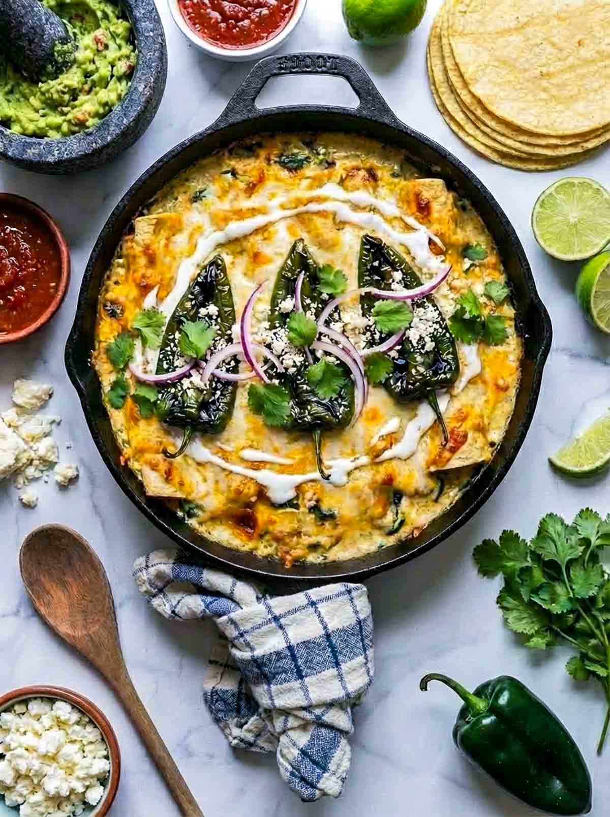 Poblano chicken enchilada made in a skillet and placed on a white marble surface.