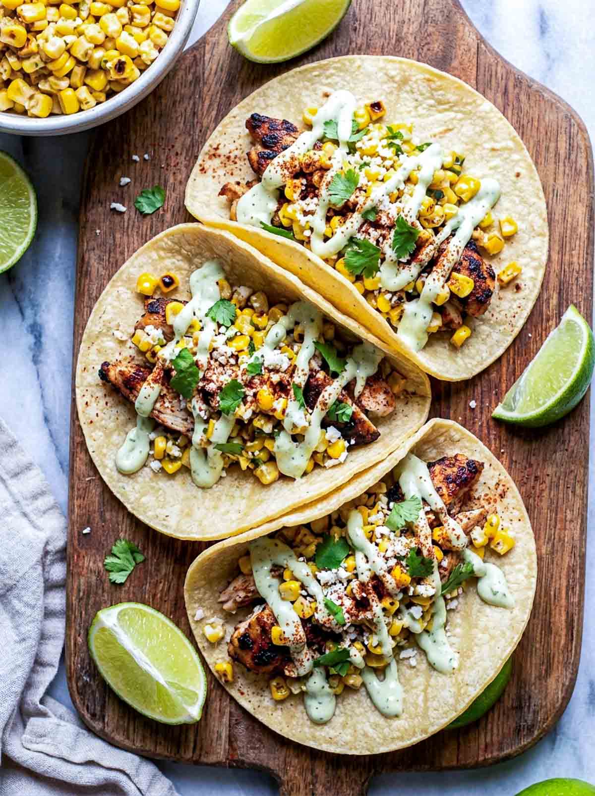 Stree corn chicken tacos placed on a wooden board.