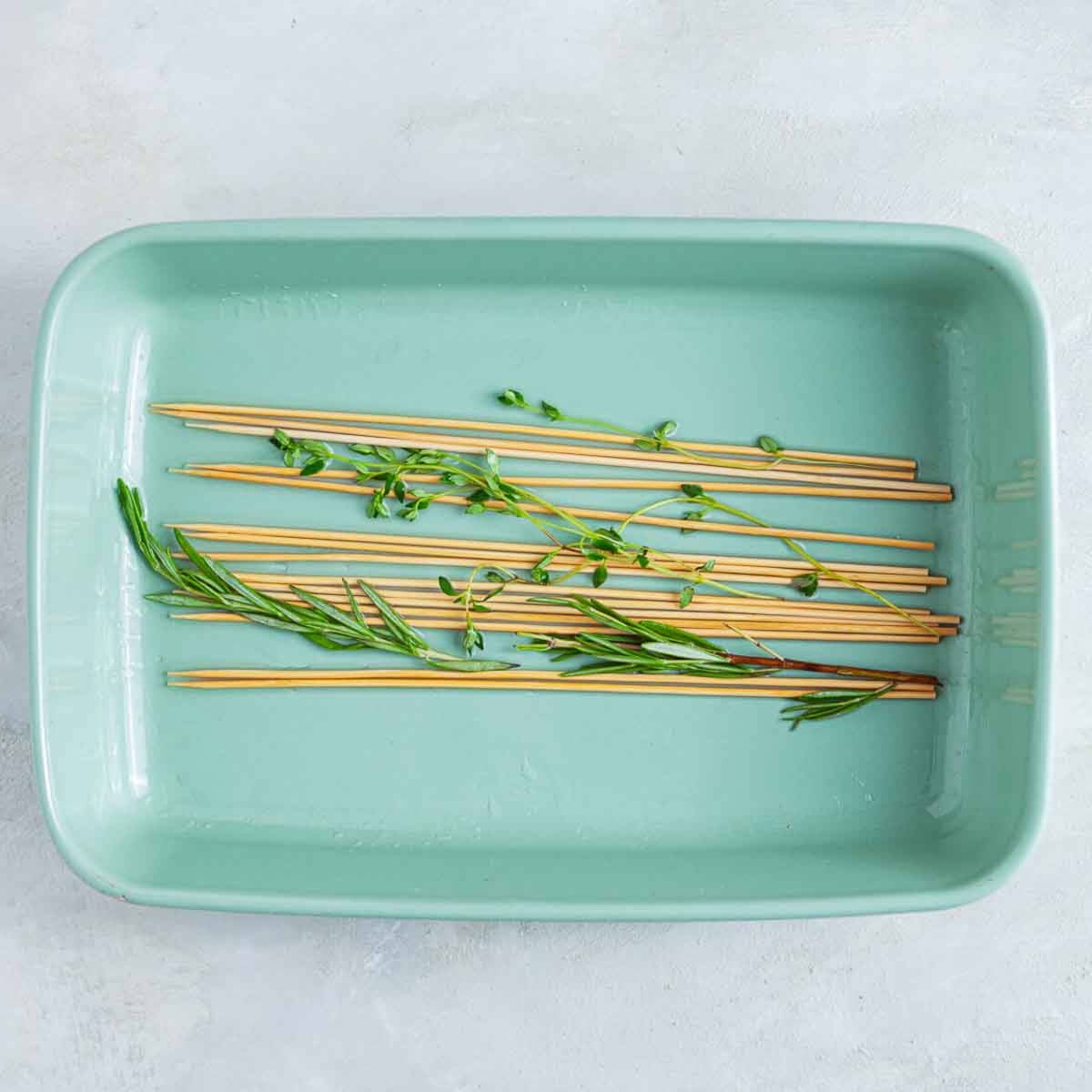 Wooden skewers with fresh herbs soaking in tray