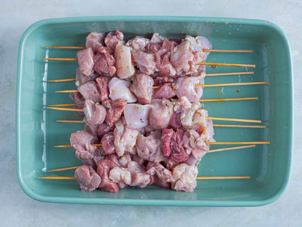 Skewers threaded with marinated chunks of raw meat, ready for grilling
