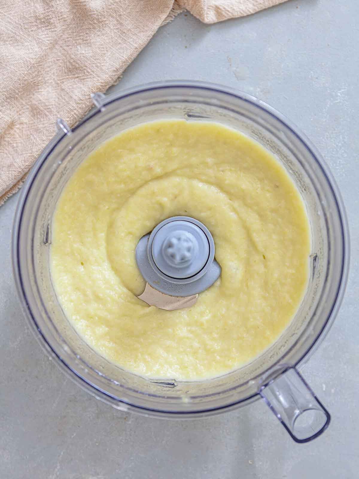 A blender filled with a smooth, creamy mixture of potatoes and leeks, pureed into a thick soup consistency