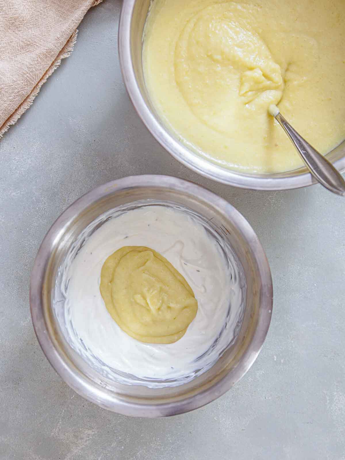 A bowl of thick, blended potato-leek mixture being added into a separate bowl of cream—showing the step where the soup base is combined with the creamy mixture to achieve a smooth, rich consistency