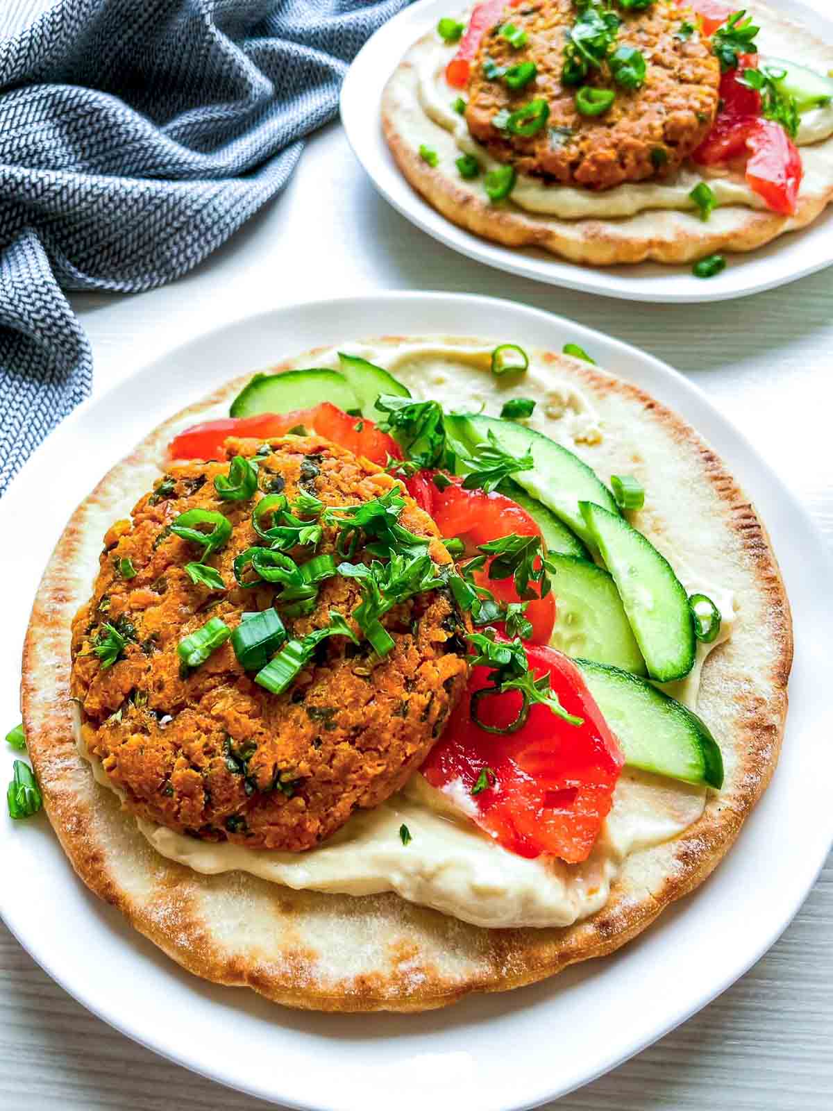 Side view of falafel pita with cucumber, tomato, and creamy sauce.