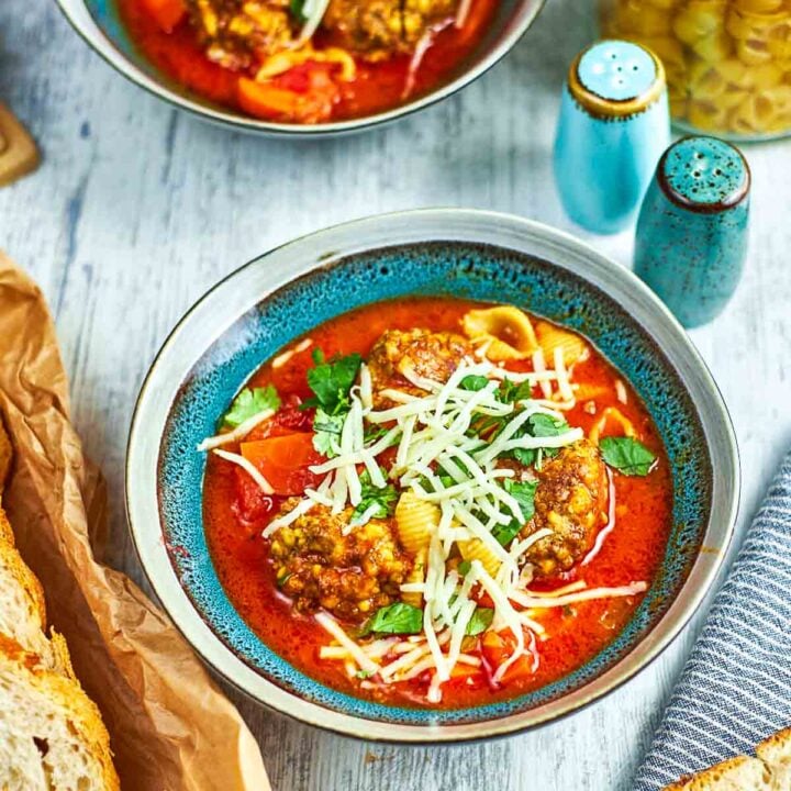 Italian meatball soup with pasta and shredded cheese