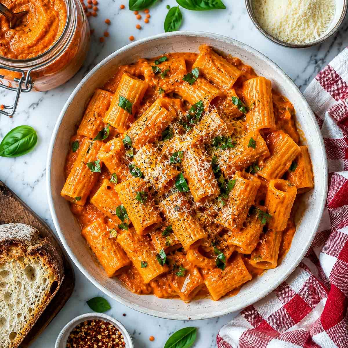 Creamy red lentil pasta sauce served with rigatoni, parmesan, and fresh basil.