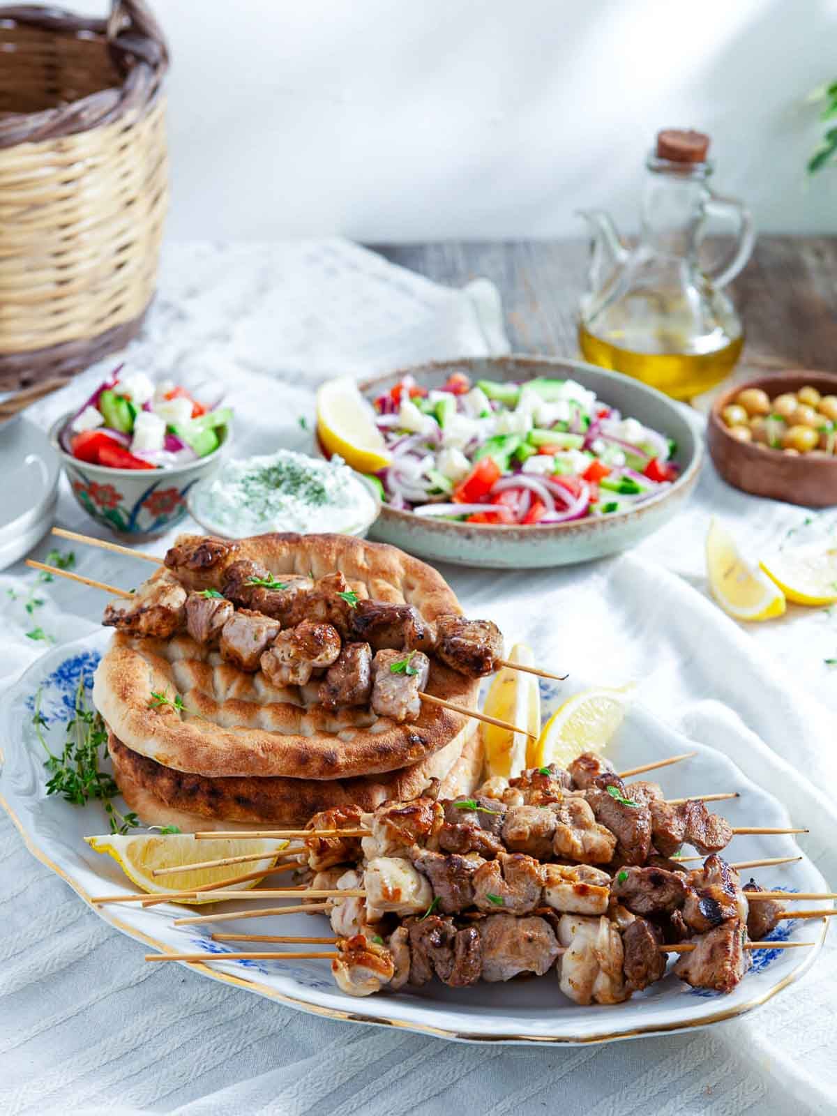 Grilled meat skewers served on warm flatbread, topped with fresh vegetables and tzatziki sauce, ready to eat.